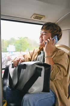 Happy smiling young man talking on mobile phone traveling in public transport.