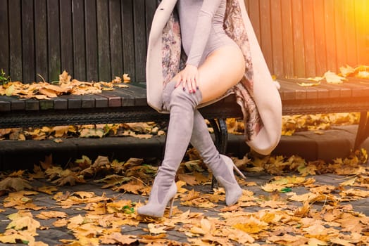 Young beautiful dark-haired woman with a slender figure posing in lingerie and a classic coat in an autumn park