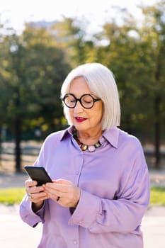 senior woman using mobile phone outdoors, concept of technology and elderly people leisure