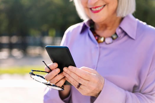 unrecognizable senior woman smiling happy using mobile phone outdoors, concept of technology and elderly people leisure