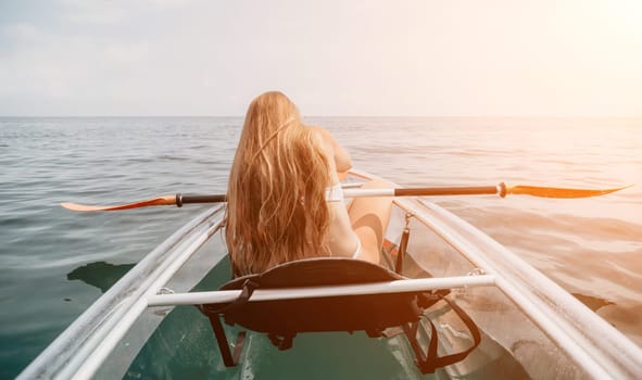 Woman in kayak back view. Happy young woman with long hair floating in transparent kayak on the crystal clear sea. Summer holiday vacation and cheerful female people having fun on the boat.