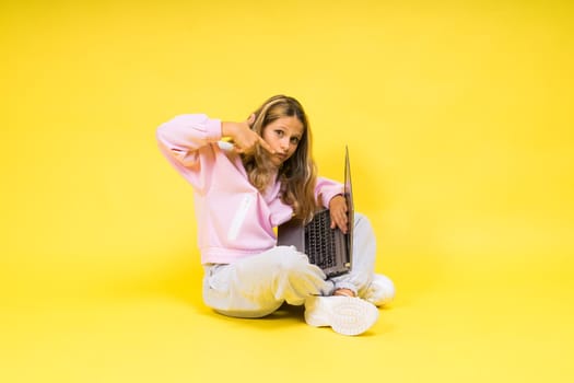 Teenager girl with notebok computer laptop sitting in a studio