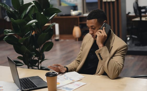 Man sitting by table working on laptop computer.