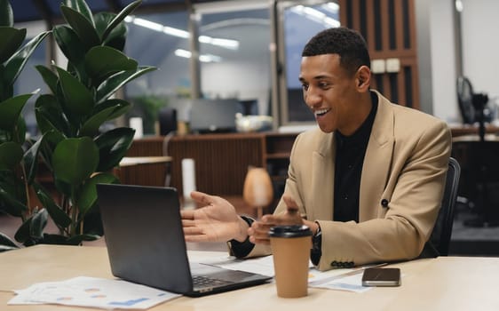 Man sitting by table working on laptop computer.