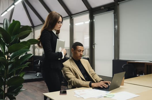 Man sitting by table working on laptop computer.