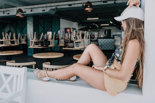 Happy woman portrait in cafe. Boho chic fashion style. Outdoor photo of young happy woman with long hair, sunny weather outdoors sitting in modern cafe