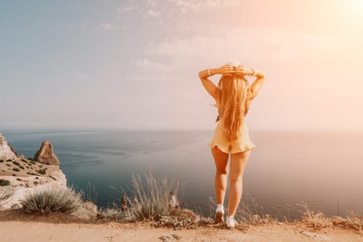 Woman travel sea. Happy tourist taking picture outdoors for memories. Woman traveler looks at the edge of the cliff on the sea bay of mountains, sharing travel adventure journey.