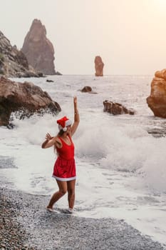 Woman travel sea. Young Happy woman in a long red dress posing on a beach near the sea on background of volcanic rocks, like in Iceland, sharing travel adventure journey