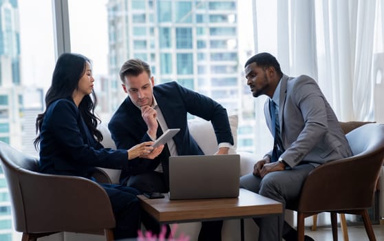 Young smart businesswoman showing data analysis to diverse investor by using tablet. Multicultural business group discussing and investing in start up project. Modern office. Meeting. Ornamented.