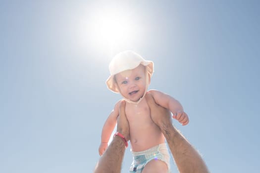 A heartwarming scene as a father lifts his baby towards the sunny sky, symbolizing love and playfulness. Concept of paternal affection and happy moments