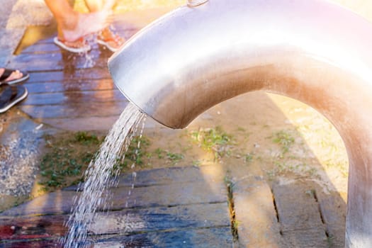 Place for washing the feet on the beach in sunny day. Water jet from a modern big tap.