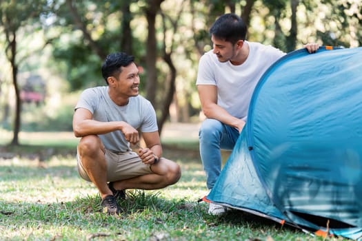 LGBTQIA Gay couple camping together in woods for holidays and relax on guitar together.