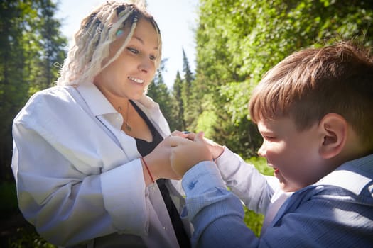 Young fat teenage boy playing with phone and mother swears, demands to stop it in a park. Blogger, gamer, streamer son online on Internet and conflict