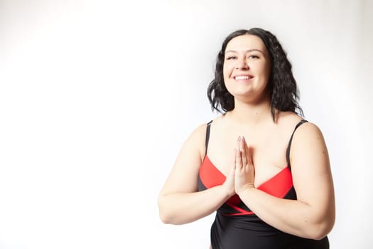 Portrait of attractive dreamy thick woman in red black swimsuit posing on white background. Body positive, photoshoot, selfie. Funny plus size model