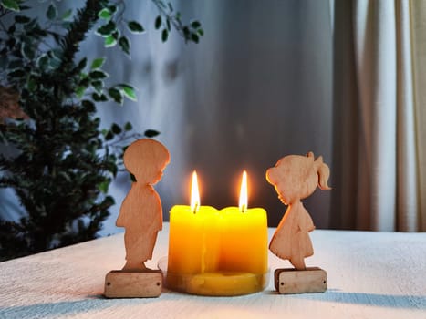 Wooden toys of boy and girl with yellow candles. Couple in love on Valentine's Day. Celebration of love and friendship. Card, background