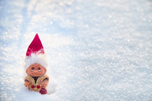Cute little funny dwarf in the snow in the landscape in winter. Wizard on a snowy background. Christmas and New Year