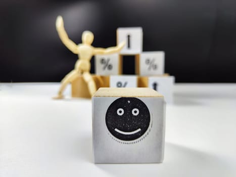 Wooden cubes in a column and row with white signs with a smiley sign, an arrow, a percentage. The concept of positivism. Positive thinking leads to the achievement of results and profits