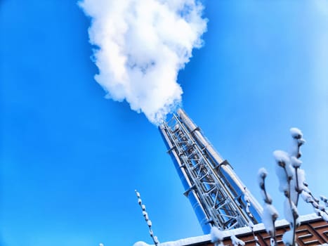 Air pollution by smoke coming out of two factory chimneys. White clouds of smoke against a blue sky background