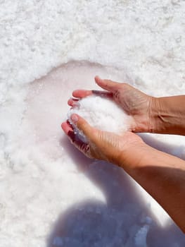 Womans hands with salt in her hands against the backdrop of salt lake. High quality photo