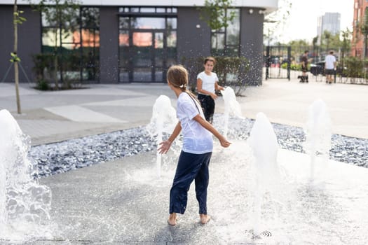 Cute young sisters playing in fountains. Children having fun with water on sunny summer day. Active leisure for kids. High quality photo