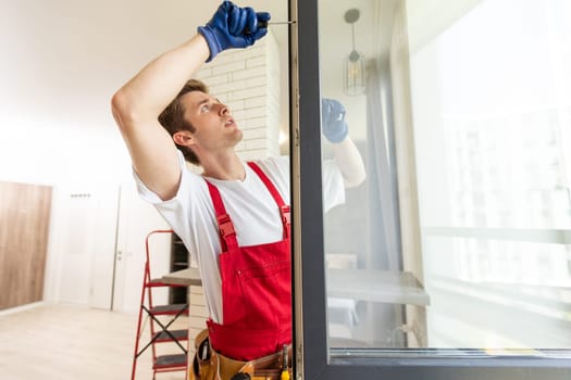 Worker installing plastic window indoors, closeup view.