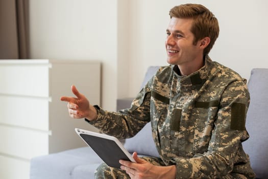 Happy young soldier holding a computer tablet.
