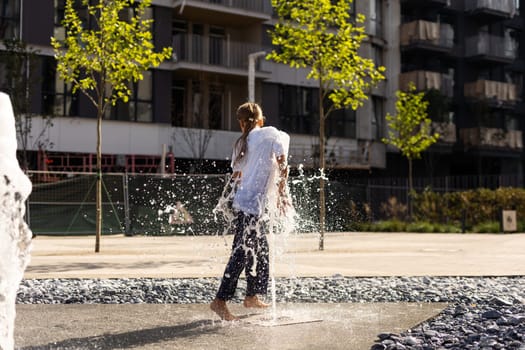 Cute young sisters playing in fountains. Children having fun with water on sunny summer day. Active leisure for kids. High quality photo