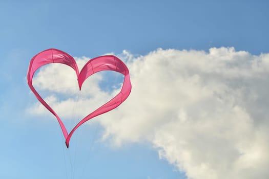 Pink heart kite is flying in the sky