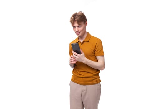 a young guy with short red hair dressed in a summer T-shirt uses applications in a smartphone.