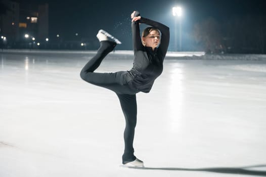 Beautiful young woman ice skating and performing short program over city outdoor ice arena. Winter activities concept