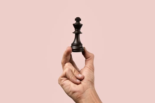 Black male hand holding a queen chess figure isolated. High quality photo