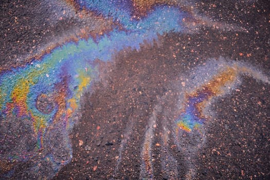 Bright spot splash of oil or gasoline on asphalt after rain.