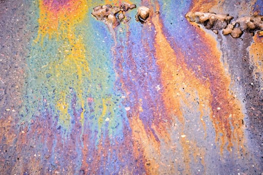A bright spot of oil or gasoline splash on the asphalt after the snow melts.