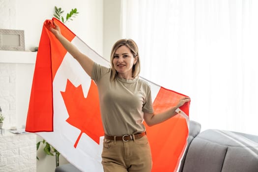 beautiful smiling woman covered in canadian flag looking at camera isolated on white. High quality photo