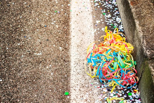 Close up colorful confetti and streamers at the street after Carnival parade