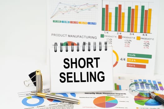 Business concept. On the table are reports with graphs and a notepad with the inscription - Short selling