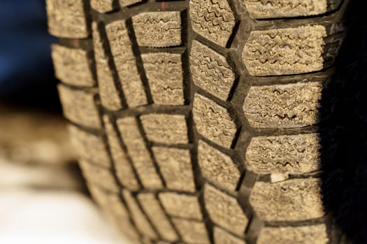 Winter tire. Close-up of the tread of a winter car tire on the road in winter.