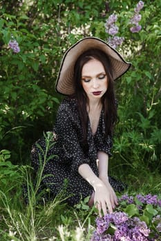 A fashionable girl with dark hair, a spring portrait in lilac tones in summer. Bright professional makeup