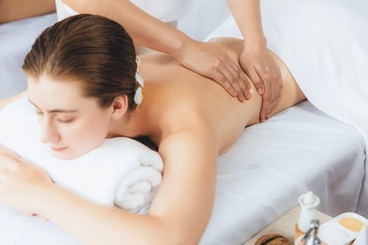 Caucasian couple customer enjoying relaxing anti-stress spa massage and pampering with beauty skin recreation leisure in day light ambient salon spa at luxury resort or hotel. Quiescent