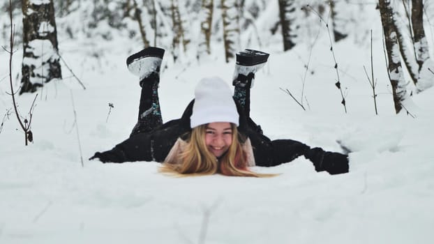 A girl falls on the snow in winter in the forest