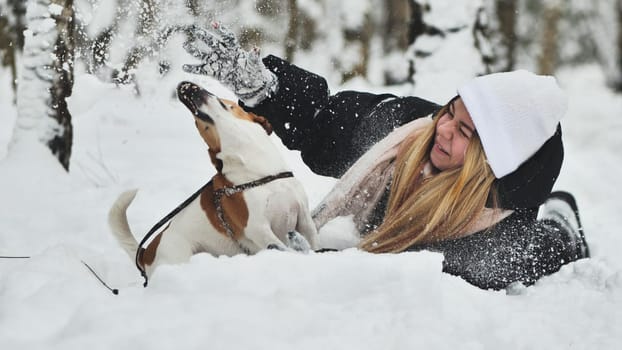 A girl playing with her Jack Russell Terrier dog in the snow