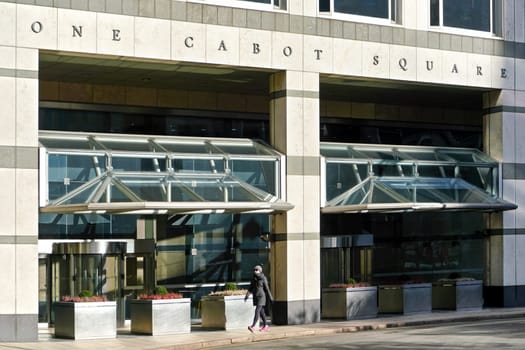 London, United Kingdom - February 03, 2019: Unknown woman walks in front of One Cabot Square London at Canary Wharf on sunny day. Credit Suisse bank resides at this building