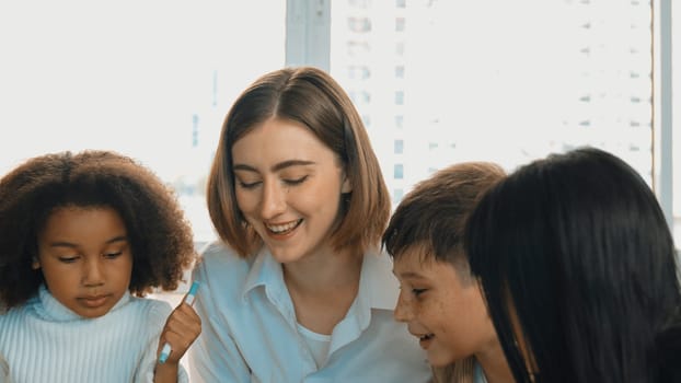 Happy diverse student and smart teacher drawing and coloring by using marker at drawing book. Multicultural smart learner using drawing book while talking to skilled caucasian instructor. Erudition.