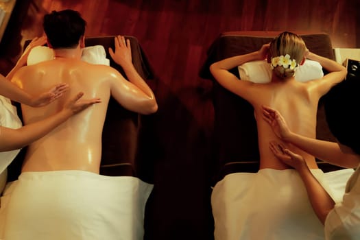 Top view couple customer enjoying relaxing anti-stress spa massage and pampering with beauty skin recreation leisure in warm candle lighting ambient salon spa at luxury resort or hotel. Quiescent
