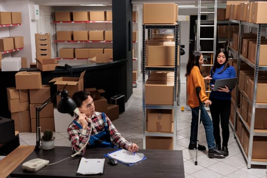 Delivery operators managing warehouse product audit in storage room. Retail industry storehouse employees working together, tracking parcel transportation online on laptop
