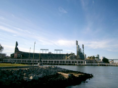 San Francisco - October 9, 2011: Clear view of Oracle Park, home to the San Francisco Giants, from across McCovey Cove. The photo shows the calm waters of the cove reflecting the sky, and the rocky shoreline at the bottom. The photo also shows the distinctive architecture and stadium lights of Oracle Park. 