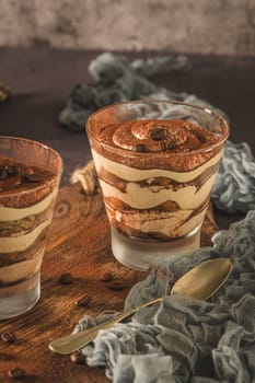 Delicious italian dessert tiramisu in a glasses on a dark slate, stone or concrete background.