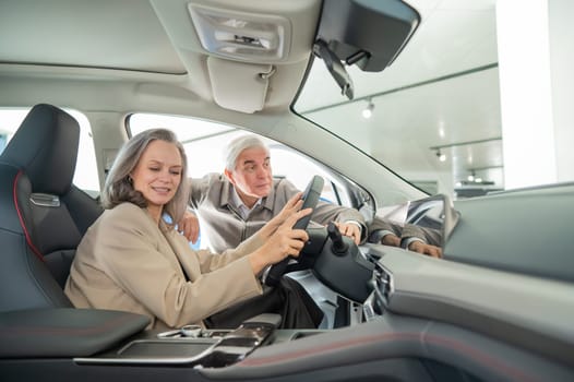 An elderly couple chooses a new car at a car dealership. Mature woman driving