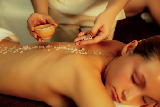 Closeup couple customer having exfoliation treatment in luxury spa salon with warmth candle light ambient. Salt scrub beauty treatment in Health spa body scrub. Quiescent