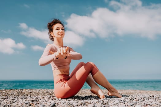 Young woman with long hair in white swimsuit and boho style braclets practicing outdoors on yoga mat by the sea on a sunset. Women's yoga fitness routine. Healthy lifestyle, harmony and meditation